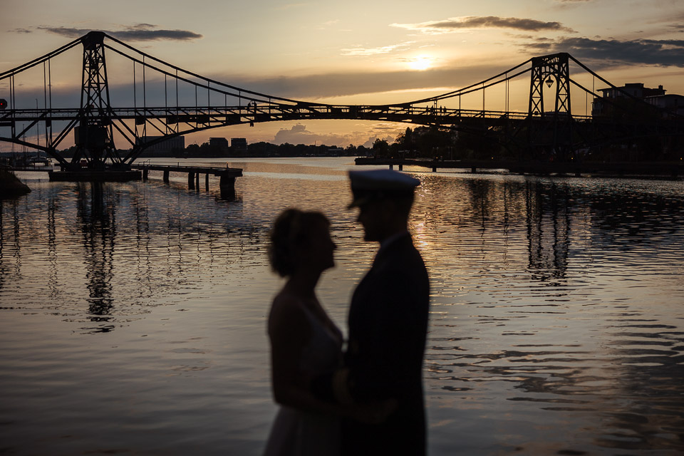 Hochzeitspaar steht vor der KW Brücke bei Sonnenuntergang